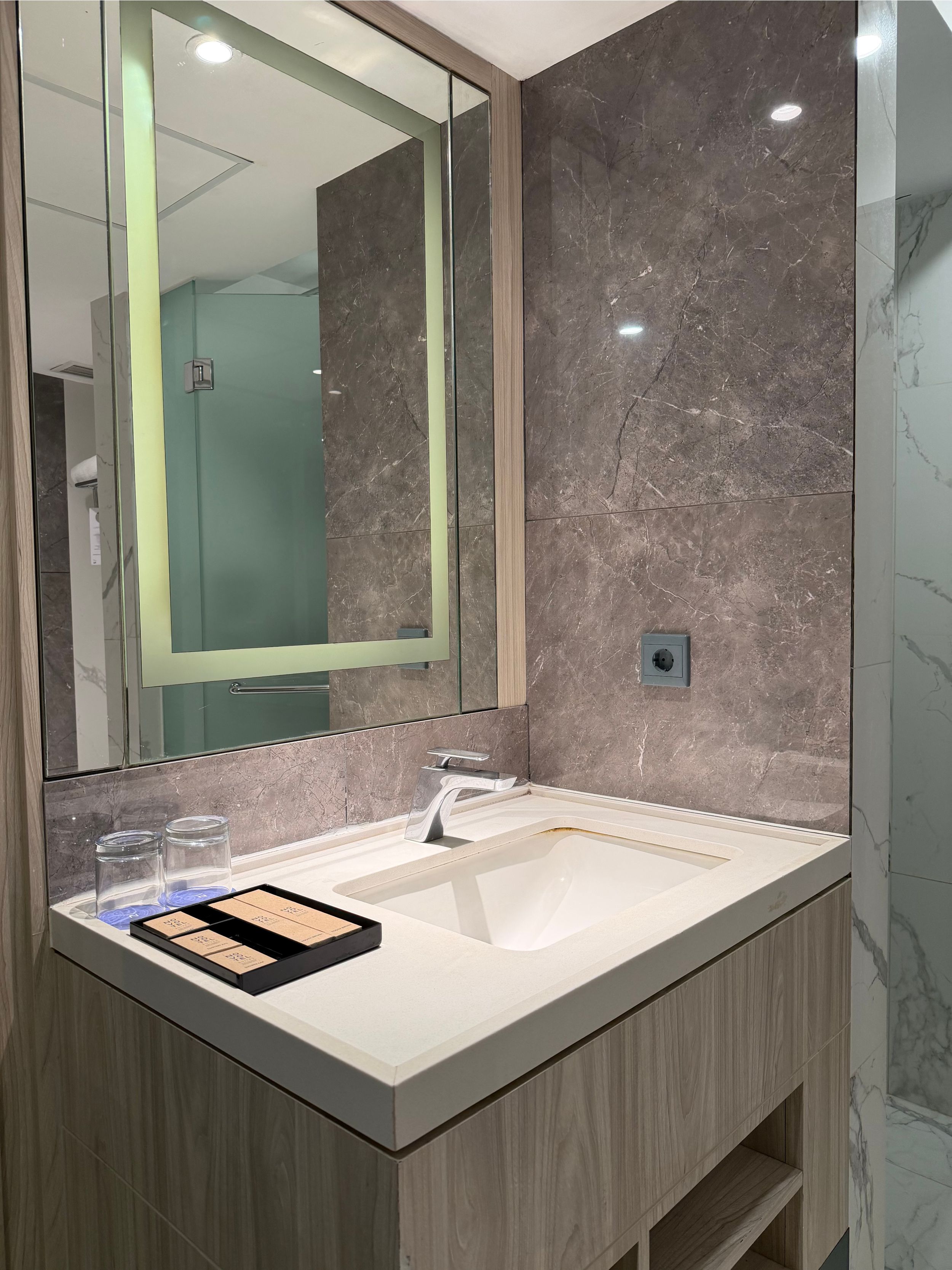 Temukan rahasia kemewahan visual Hotel Novotel. Cermin backlit LED dan perpaduan marmer-kayu yang menciptakan pengalaman relaksasi layaknya spa pribadi di rumah Anda