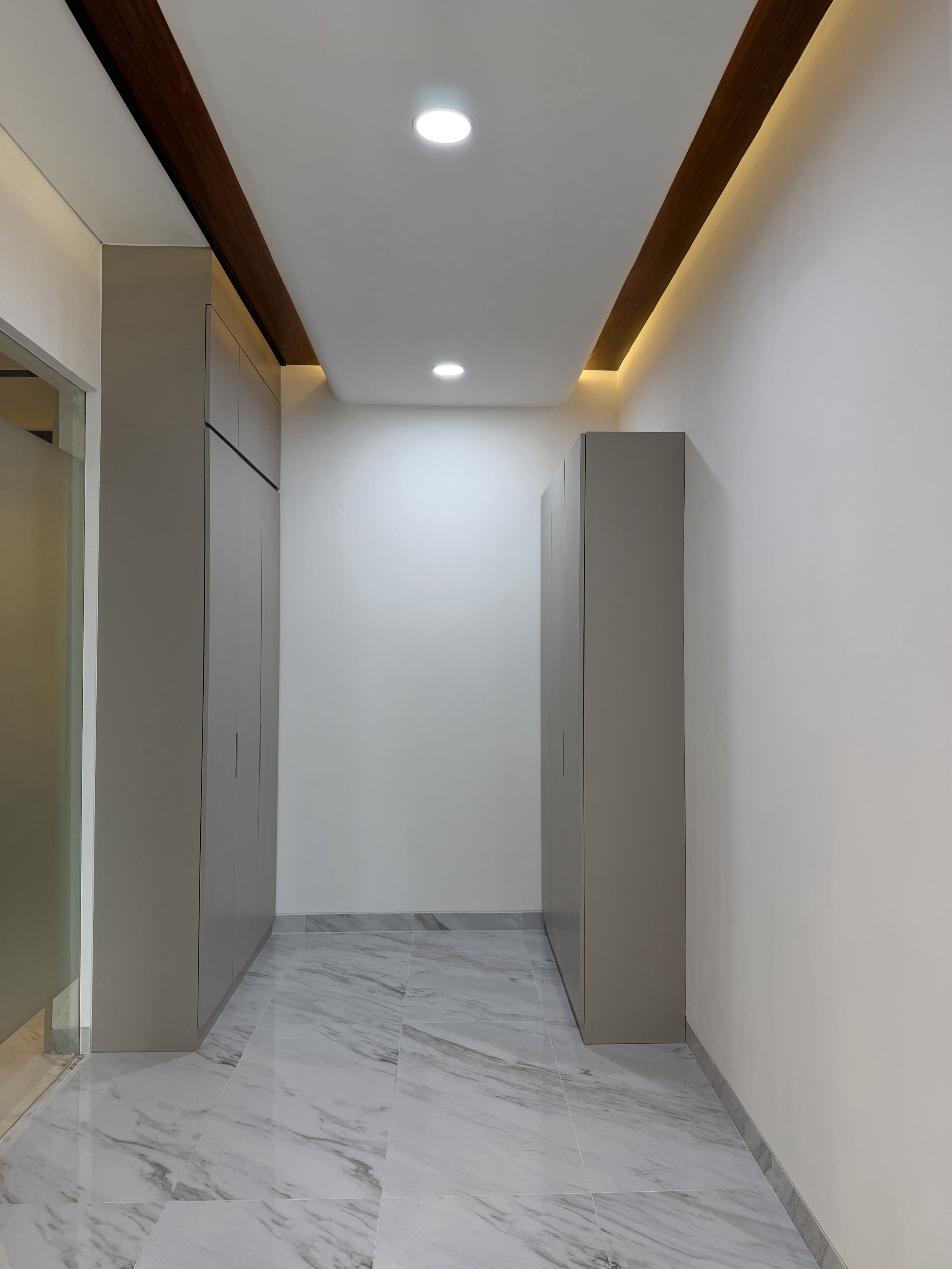 Desain koridor fungsional dengan lemari built-in dan lantai marmer di Office Cahaya Group