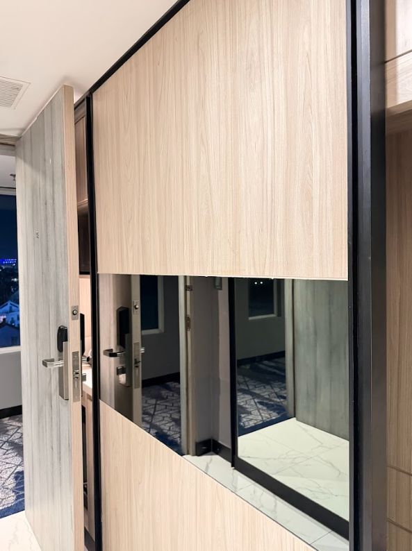 Wallpanel kayu terang dengan cermin di samping pintu Novotel Jogjakarta
