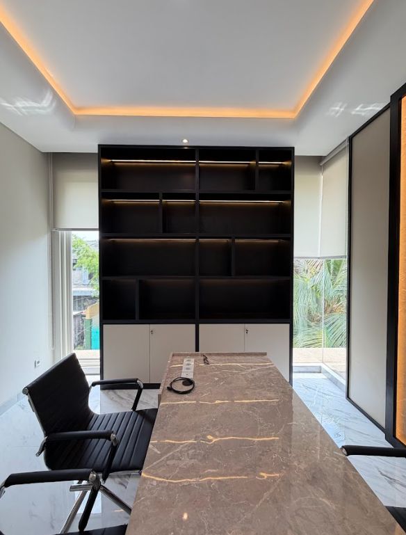 Interior kantor eksekutif modern dengan meja marmer, kursi kulit hitam, dan lemari custom berpencahayaan LED oleh Tuka Interior